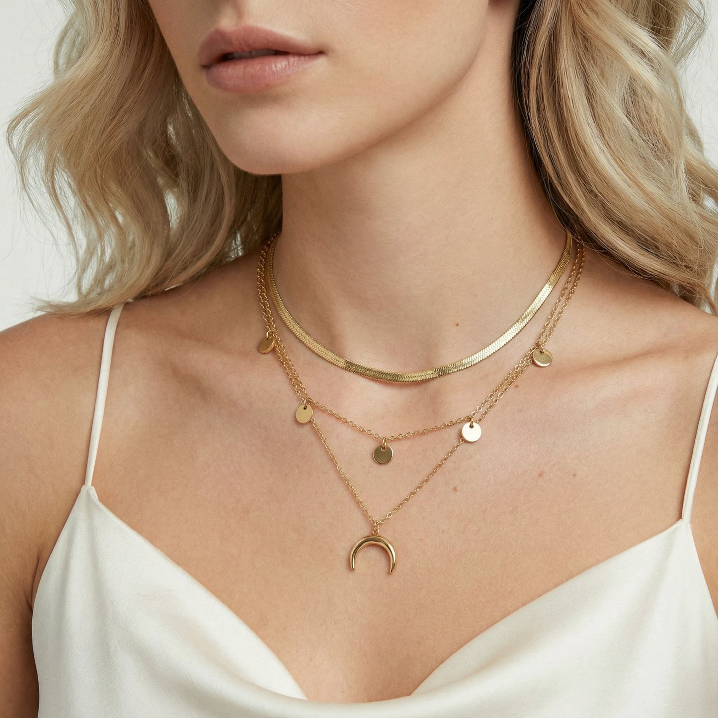Close-up of a woman wearing gold necklaces with a plain background