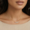 Gold necklace with small diamonds on a person wearing a beige top