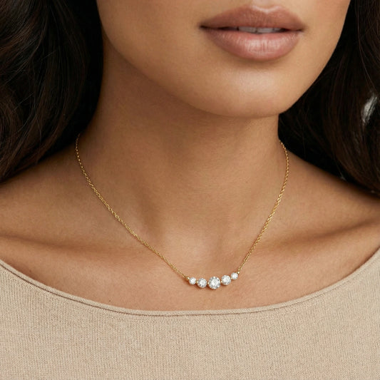 Gold necklace with small diamonds on a person wearing a beige top