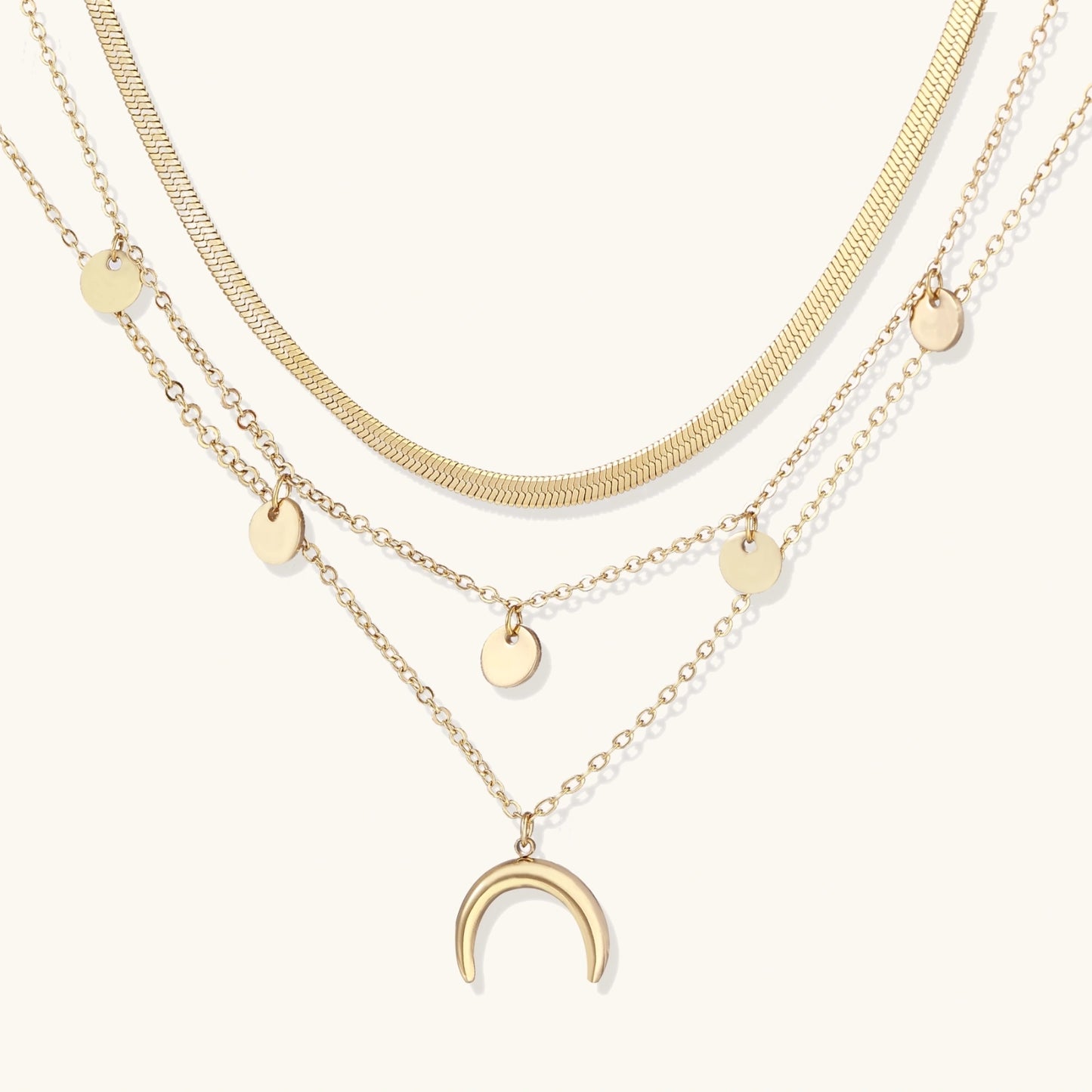Three gold necklaces with various pendants on a white background